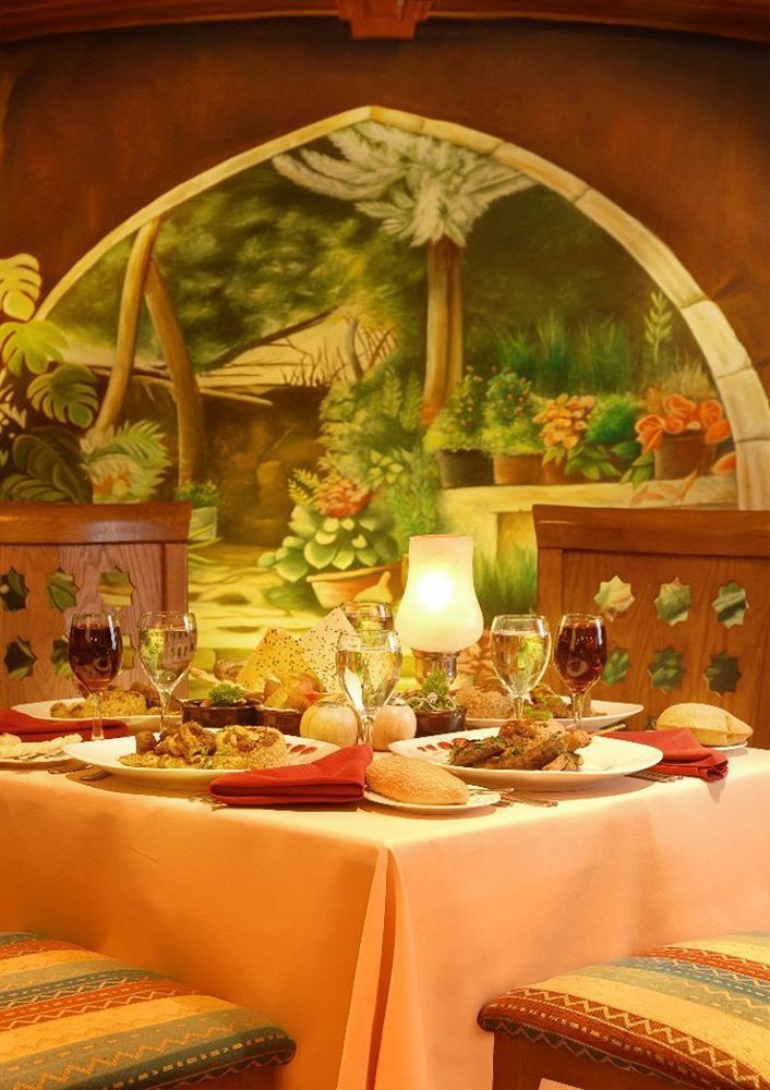 Sunrise Alex Avenue Hotel Aleksandria Zewnętrze zdjęcie The photo depicts a beautifully arranged dining table set against a vibrant mural of a garden. The table features a variety of dishes, likely a mix of main courses and sides, elegantly presented on white plates. There are also several glasses, includ