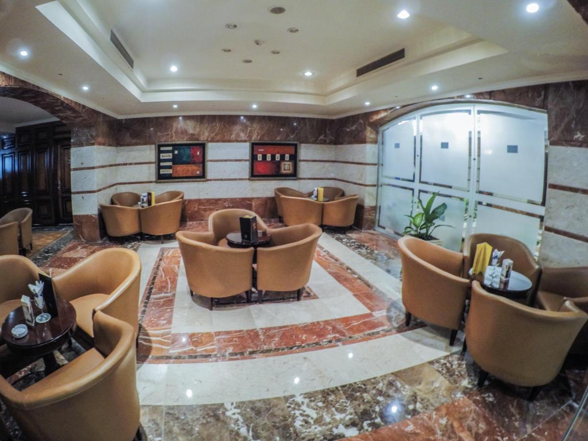 Sunrise Alex Avenue Hotel Aleksandria Zewnętrze zdjęcie The photo depicts a stylish lounge area with several comfortable seating arrangements. There are plush, curved chairs arranged around small tables, likely intended for coffee or casual gatherings. The floor features a polished marble design, and the 
